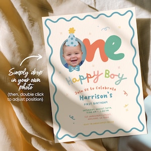 May include: A personalized first birthday invitation with a photo of a baby wearing a party hat and bow tie. The invitation features the words "Happy Boy" and event details in colorful, playful fonts. The invitation is on a cream background with a blue border.