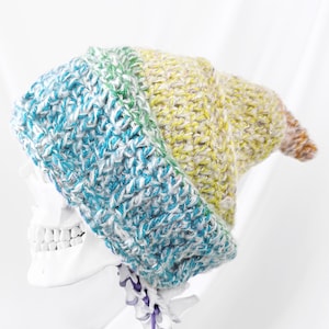 May include: A colorful crocheted beanie hat with a rainbow gradient of blue, green, yellow, and orange. The hat is made with a chunky yarn and has a slouchy fit.