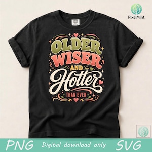 May include: Black t-shirt with the text "Older, Wiser, and Hotter Than Ever" in a retro design. The text is in green, red, and white with decorative elements. A fun, casual tee for everyday wear.