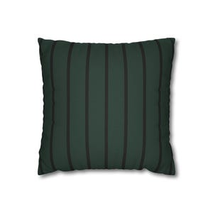 May include: Square throw pillow with a dark green background and vertical black stripes. The pillow has a soft, textured appearance and is designed for decorative use on a bed or sofa. The pillow is a square shape.