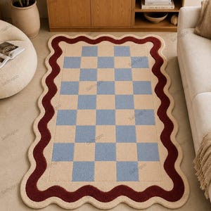 May include: A rectangular rug with a checkerboard pattern in light blue and beige, framed by a wavy burgundy border. The rug is placed on a light-colored floor, with furniture visible in the background.