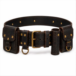 May include: A dark brown leather utility belt featuring a brass buckle, multiple pouches with flap closures, brass rivets, and integrated D-rings. The belt is constructed with thick, textured leather and includes a cylindrical holder on the front.