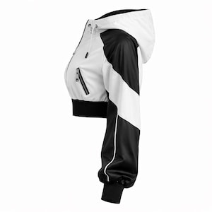 May include: Cropped white and black jacket with a hood. The jacket features a white body with black accents on the sleeves and sides. It has a zipper closure and black ribbed cuffs and hem. The jacket is designed with a sporty aesthetic.