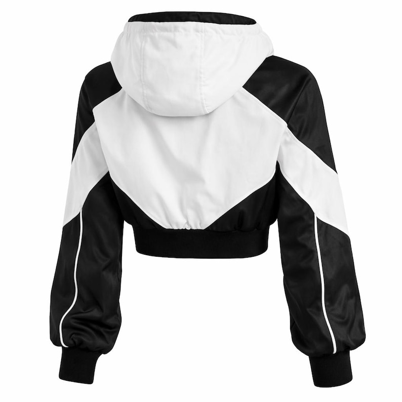 May include: A cropped black and white jacket with a hood. The jacket features a color-block design with white and black panels, white piping, and black ribbed cuffs and hem. The back view shows the jacket's design.