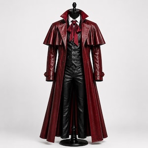 Pode incluir: Um sobretudo de couro bordô com um design de ombro tipo capa, combinado com um colete preto, calças e uma gravata vermelha. A roupa é exibida em um manequim preto, mostrando um estilo gótico ou de inspiração vitoriana.