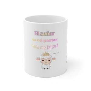 Puede incluir: Taza de cerámica blanca con el texto en español "El señor es mi pastor nada me faltará" en rosa, amarillo y morado. Un cordero de dibujos animados con una corona dorada está debajo del texto. La taza tiene un acabado brillante.