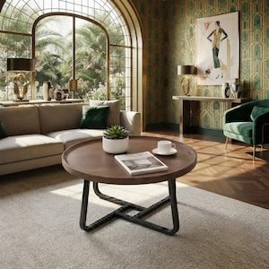 May include: A round wooden coffee table with a dark brown circular top and a black metal base featuring an interlocking geometric design. The table holds a small potted succulent in a white ceramic planter, a white ceramic cup, and a magazine.
