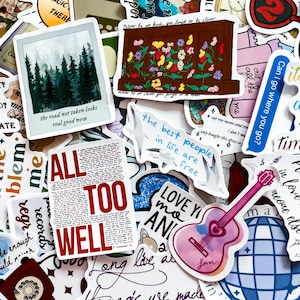 Può includere: Una collezione di adesivi colorati con vari disegni e testo. Gli adesivi includono una scena di foresta, un'illustrazione floreale, una chitarra con la parola "Lover" e testi che dicono "All Too Well" e "The best people in life are free."
