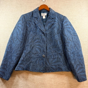 Puede incluir: Un blazer azul con un estampado floral. La chaqueta tiene un cierre de un solo botón y un cuello con solapas. La tela tiene un aspecto texturizado. La marca "Pendleton" es visible en una etiqueta dentro de la chaqueta.