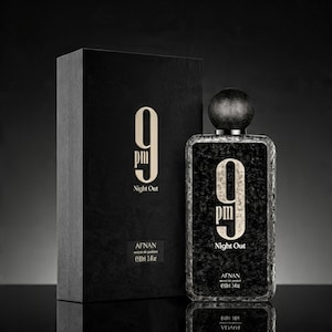 May include: A rectangular black perfume bottle and its matching box, both featuring the text 9 pm Night Out in gold lettering. The bottle has a textured black surface and a round black cap. The label indicates Afnan and 3.4 fl oz.