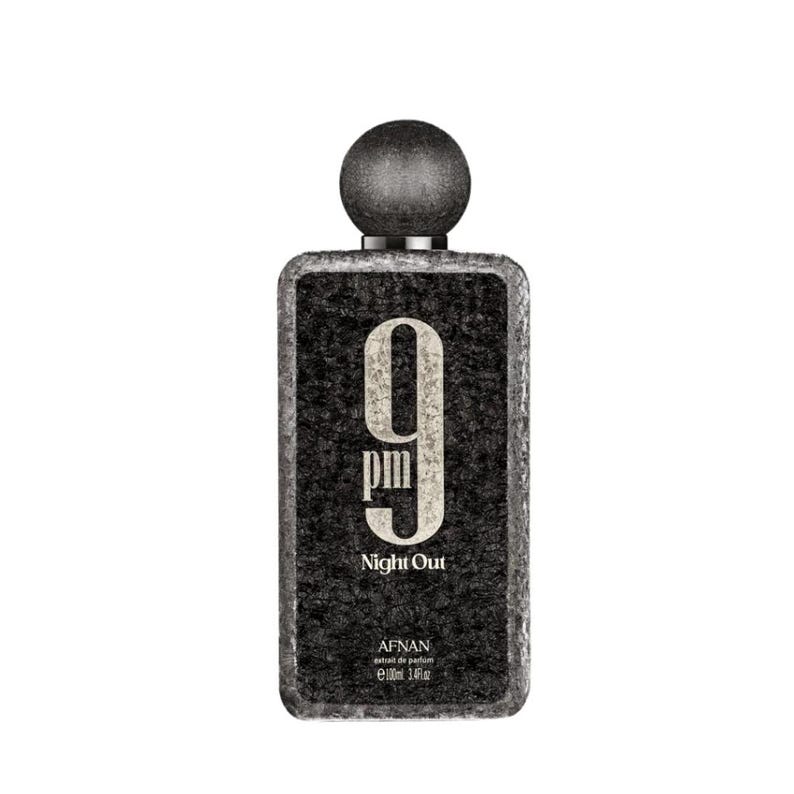 May include: A rectangular perfume bottle with a textured black surface, featuring a large white '9 pm' graphic, the text 'Night Out', and 'AFNAN extrait de parfum 100ml 3.4fl.oz' printed on the front. It has a round, dark gray textured cap.