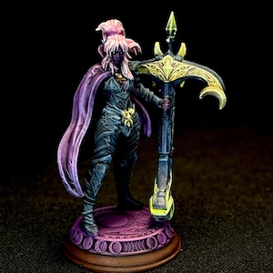 May include: A miniature fantasy figure of a warrior with purple skin, wearing dark armor and a flowing purple cape. The figure holds a large, ornate crossbow with gold and yellow accents. The base is circular with a decorative design.