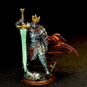 May include: A miniature figurine of a knight in dark armor, wearing a gold crown and holding a glowing green sword. The knight has a red cape and stands on a round, brown base. The figurine is a fantasy-themed collectible.