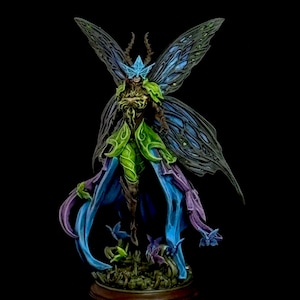May include: A detailed fantasy figurine of a winged humanoid figure wearing a bright blue mask, green armor, and flowing blue and purple robes. The figure features large, dark blue insect-like wings and stands on a base decorated with small plant elements.