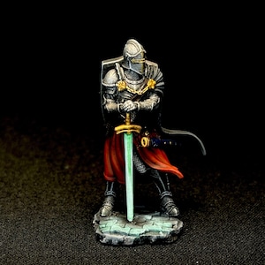 May include: A miniature knight figurine in full armor, holding a glowing green sword. The knight wears a helmet, chainmail, and a red cape. The figure stands on a stone base, with gold accents on the armor. The background is black.