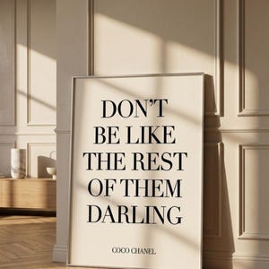 Puede incluir: Impresi&oacute;n enmarcada con la cita "DON'T BE LIKE THE REST OF THEM DARLING" en texto negro sobre fondo crema. La impresi&oacute;n est&aacute; firmada "COCO CHANEL" en la parte inferior. El marco es plateado y la impresi&oacute;n est&aacute; apoyada contra una pared.