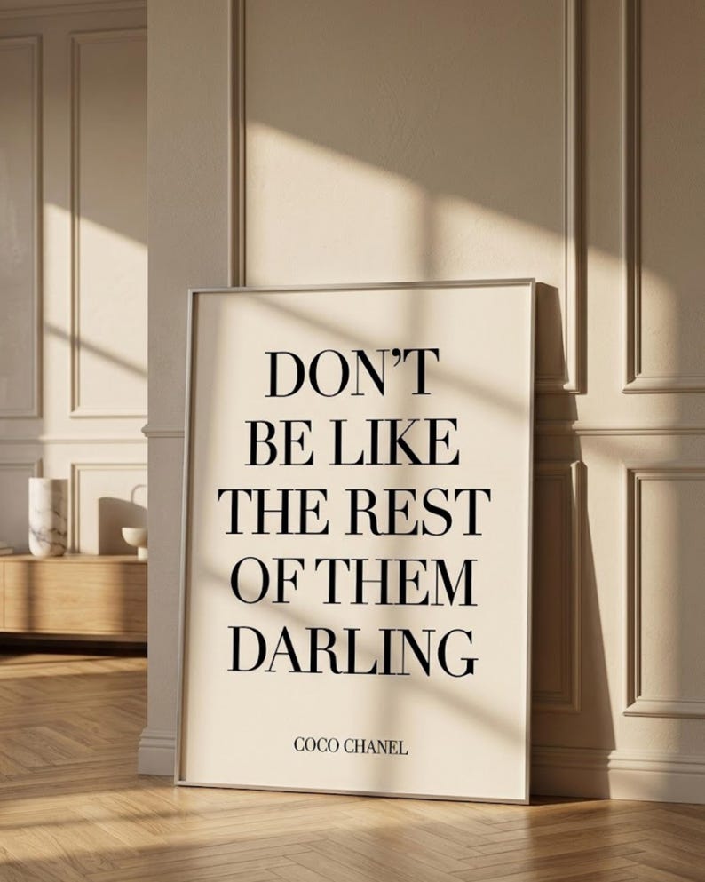 Puede incluir: Impresi&oacute;n enmarcada con la cita "DON'T BE LIKE THE REST OF THEM DARLING" en texto negro sobre fondo crema. La impresi&oacute;n est&aacute; firmada "COCO CHANEL" en la parte inferior. El marco es plateado y la impresi&oacute;n est&aacute; apoyada contra una pared.