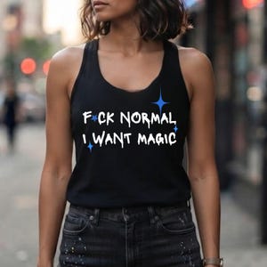 Puede incluir: Una camiseta de tirantes negra con espalda nadadora que presenta el texto blanco F*CK NORMAL I WANT MAGIC y estrellas azules de cuatro puntas. El gráfico está centrado en el pecho de la prenda sin mangas, combinada con vaqueros oscuros.