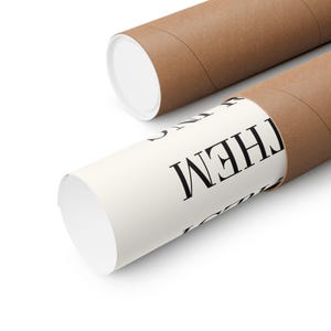 Puede incluir: Dos tubos de cart&oacute;n marr&oacute;n para p&oacute;ster con tapas blancas. Uno de los tubos est&aacute; parcialmente desenrollado, revelando un papel blanco con la palabra "THEM" impresa en negro. El otro tubo est&aacute; cerrado.