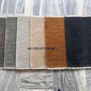 Könnte beinhalten: Eine Auswahl rechteckiger Teppichmuster in verschiedenen Farben, darunter Braun, Grau, Beige und Dunkelblau. Die Muster sind nebeneinander angeordnet, mit dem Text "ART COLLECTION INC." sichtbar. Die Teppiche haben eine strukturierte Oberfläche.