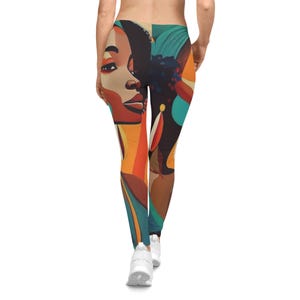 May include: Leggings featuring a colorful abstract design of a woman's face and form. The leggings have a high waist and are primarily in shades of orange, teal, brown, and black. The leggings are paired with white sneakers.