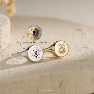 May include: Two metal signet rings, one silver-toned and one gold-toned, each featuring a custom engraved line art portrait of a pet. The silver ring displays a dog, while the gold ring shows a cat. Text reads Custom Your Pet Line Art.