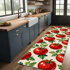Puede incluir: Una alfombra de cocina rectangular con un patrón repetido de grandes tomates rojos y hojas verdes sobre un fondo crema. La alfombra está colocada sobre un suelo de madera, añadiendo un toque decorativo a la cocina.