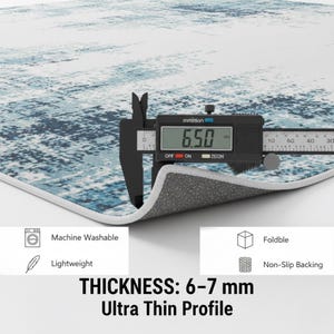 K&ouml;nnte beinhalten: Nahaufnahme eines Teppichs mit blauem und wei&szlig;em abstraktem Design. Die Dicke des Teppichs wird mit einem digitalen Messschieber auf 6,5 mm gemessen. Der Text auf dem Bild lautet "Maschinenwaschbar", "Leicht", "Faltbar", "Rutschfeste R&uuml;ckseite" und "Dicke: 6-7 mm Ultraflaches Profil."
