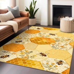 May include: A yellow and cream hexagonal patterned rug with bee and honeycomb designs. The rug features various patterns, including floral, polka dot, and honeycomb, with several bee illustrations. The rug is placed on a wooden floor in a living room setting.