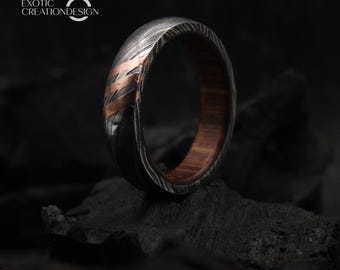 Può includere: Primo piano di un anello con esterno in metallo scuro a fantasia e un accento color rame. L'interno dell'anello è in legno marrone caldo. L'anello è su una superficie scura. Il testo "EXOTIC CREATIONDESIGN" si trova nell'angolo in alto a sinistra.