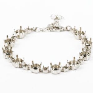 Pode incluir: Uma pulseira de metal em tom prateado com uma série de engastes de garras vazios concebidos para segurar pedras preciosas. A pulseira inclui uma secção de corrente delicada com um fecho de lagosta para um ajuste regulável no pulso.