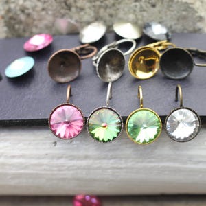 Op de afbeelding: Een verzameling ronde, facetgeslepen kristallen oorbellen in verschillende kleuren, waaronder roze, groen en helder. De oorbellen hebben metalen zettingen in antiek brons, zilver en goudtinten. Losse kristallen en oorbelcomponenten zijn ook zichtbaar.