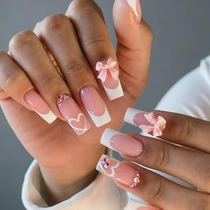 Unghie finte personalizzate rosa con french manicure, fiocco e cuoricini rosa 3D, forma quadrata, dettagli glitterati, unghie finte dolci.