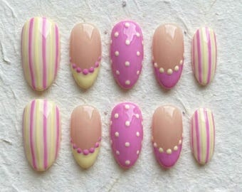 Ongles à presser pastel pastel : rayures jaunes roses, forme en amande à pois