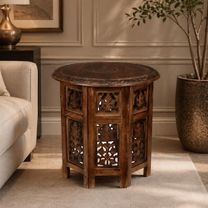May include: A dark brown, round side table with intricate carved floral designs. The table has a hexagonal base with openwork panels and a detailed tabletop. The wood has a rich, warm tone, and the design suggests a vintage or antique style.