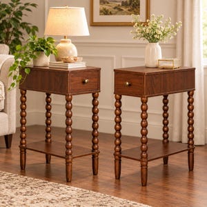 May include: Two rectangular dark wood end tables, each featuring a single drawer with a small round brass knob, a lower storage shelf, and four legs with a distinctive stacked ball or spool design. The tables have a smooth, polished finish.