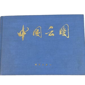 May include: A blue book with gold Chinese characters on the cover. The book is rectangular and appears to be a hardcover. The text is in a stylized font. The book is closed and appears to be in good condition.