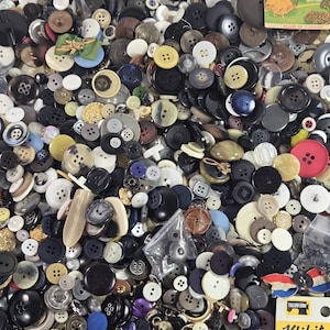 Peut inclure: Un assortiment de boutons de différentes tailles, formes et couleurs, dont noir, blanc, marron et jaune. Certains boutons ont deux ou quatre trous, d'autres ont des tiges. On trouve également des cartes de boutons vintage et un paquet d'attaches rapides Klikit.