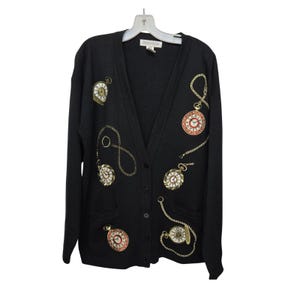 May include: Black cardigan with a V-neck and button fastening. The sweater is decorated with gold-coloured pocket watch designs and gold chain details. The pocket watches have red, white, and gold accents. It has two front pockets.