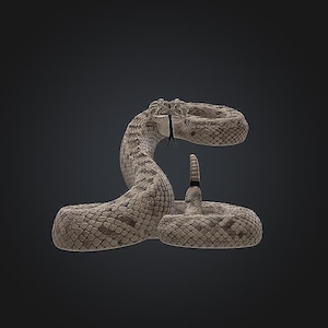 Pode incluir: Uma estatueta de cascavel enrolada com um padrão de escamas texturizado em tons de bege e castanho. A cobra está numa postura ereta e alerta com a cabeça levantada, a boca ligeiramente aberta e uma língua preta bifurcada visível.