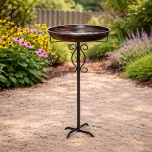 Peut inclure: Un abreuvoir &agrave; oiseaux en bronze avec une cuvette ronde, soutenu par un support en m&eacute;tal d&eacute;coratif. Le support pr&eacute;sente un design orn&eacute; et une base &agrave; trois branches. L'abreuvoir est rempli d'eau et est install&eacute; dans un jardin. Hauteur: environ 76 cm.