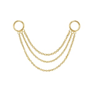 Könnte beinhalten: Eine goldfarbene Ohrkette mit drei filigranen Ketten, die von zwei kreisförmigen Ohrverbindern herabhängen. Die Ketten sind mit kleinen Ringen an den Ohrverbindern befestigt. Der Schmuck ist für Ohrpiercings konzipiert.