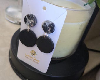 May include: Black and silver marbled stud earrings with a black disc below. The earrings are displayed on a white card with the text "Lemon Drop Design & Clay Jewellery". The earrings are hanging in front of a candle.