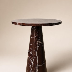 May include: A round-top side table with a dark red marble finish and white veining. The table has a conical base and is approximately 24 inches tall.