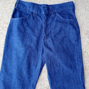 May include: A pair of dark blue denim jeans. The jeans have a classic five-pocket design with a button and zipper closure. The jeans are made of a sturdy denim fabric and have a straight leg cut. The jeans are a versatile wardrobe staple.