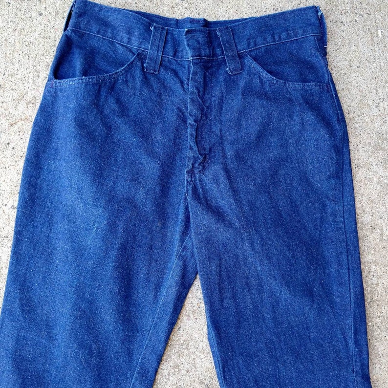 May include: A pair of dark blue denim jeans. The jeans have a classic five-pocket design with a button and zipper closure. The jeans are made of a sturdy denim fabric and have a straight leg cut. The jeans are a versatile wardrobe staple.