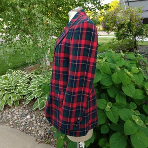 May include: A red, green, and yellow plaid blazer. The blazer has a double-breasted closure and a single button on each cuff.
