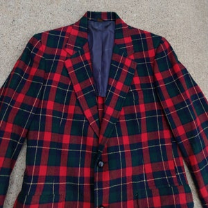 May include: A red, green, and black plaid blazer with a single button closure.