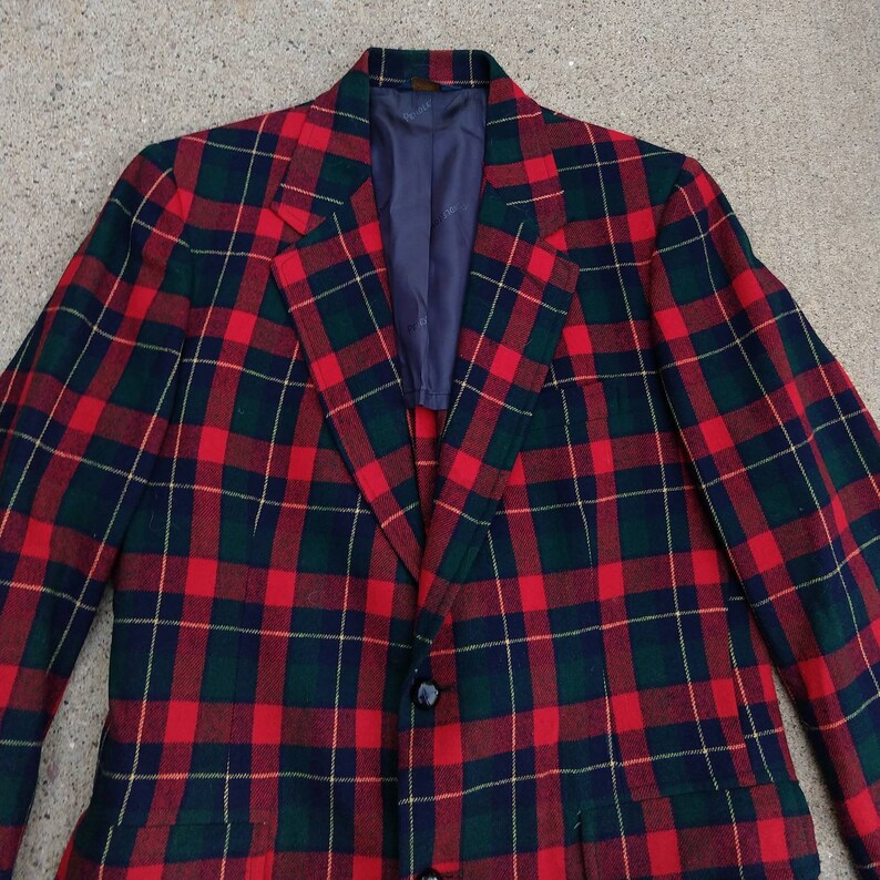 May include: A red, green, and black plaid blazer with a single button closure.