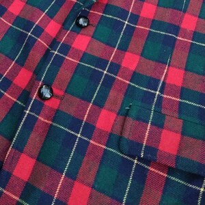 May include: Red, green, and black plaid fabric with two black buttons.